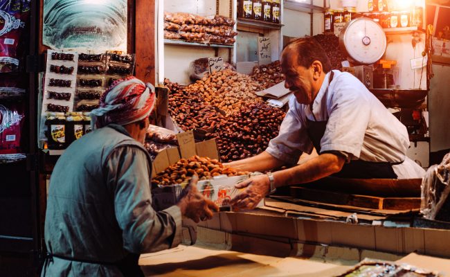 Man in a food stand passing a box to a customer.