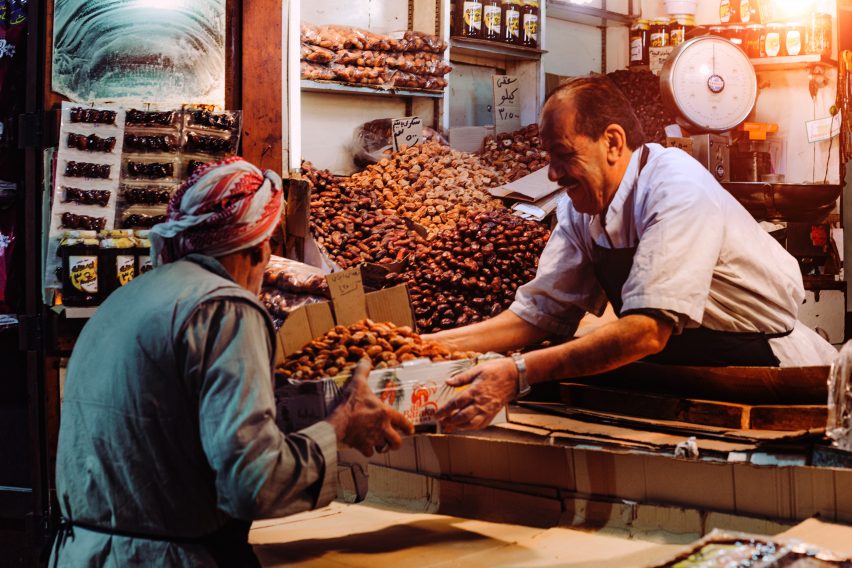 Man in a food stand passing a box to a customer.